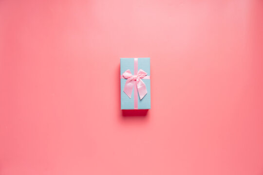 Top view photo of valentine's day decorations giftbox with silk ribbon bow on isolated pastel pink background with copyspace, concept Valentine's Day.