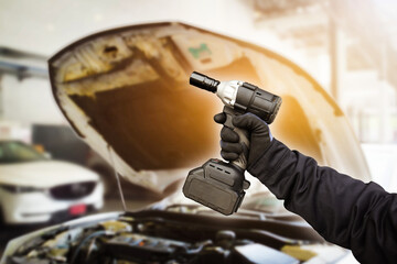 Car mechanic hand holding impact wrench cordless in car repair garage , Car maintenance service concept