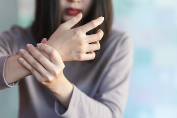 A woman touches her arm or wrist because of pain from a health problem. Health care concept.