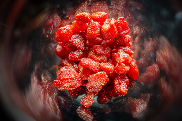 Close focus on small dried strawberries preserved inside glass jar.