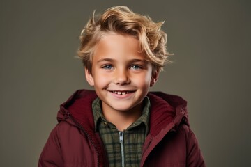 Portrait of a smiling little boy in a warm jacket. Studio shot.