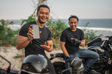 Fototapeta na wymiar asian men sitting on motorcycle and holding mockup phone