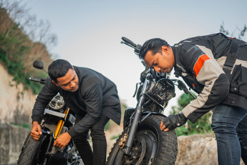 indonesian rider checking or inspecting motorbike wheel before traveling