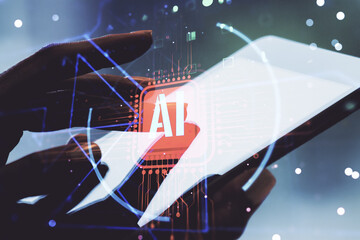 Double exposure of creative artificial Intelligence abbreviation and hand working with a digital tablet on background. Future technology and AI concept