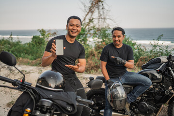 Fototapeta na wymiar asian men sitting on motorbike and holding mockup phone