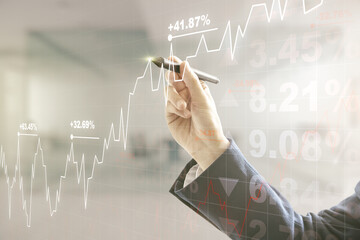 Man hand with pen working with abstract virtual financial graph on blurred office background, forex...