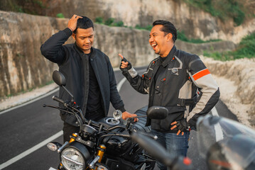 indonesian rider laughing at his friend because friend's empty fuel tank