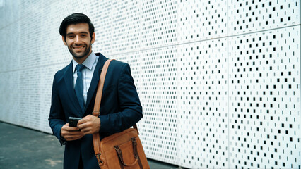 Portrait image of successful young business man looking at camera while hold phone with white...