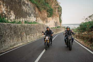 asian men having fun by riding motorcycle on the road