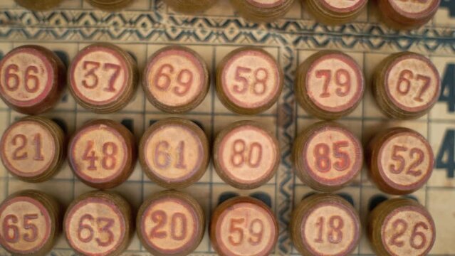 Cinematic close-up smooth zoom in shot of a Bingo wooden barrels, woody figures, on a old numbers textured background, vintage board game, professional lighting, slow motion 120 fps