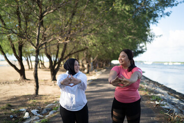 two asian women warming up together before running