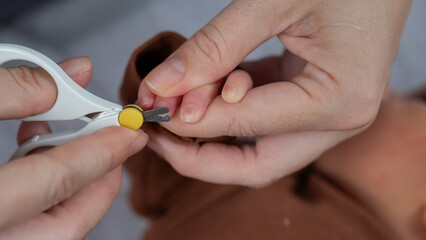 Mom cuts her newborn son's fingernails with small children's scissors.