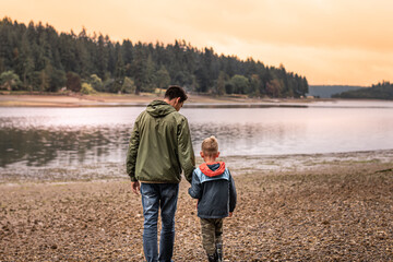 Loving father and son bonding in nature walking together in a moutain lake setting 