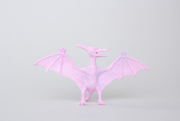 Small pterodactyl toy on gray background, little pink plastic dinosaur figurine