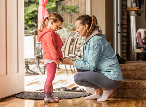 Mother getting her child dressed up in warm jacket getting ready morning routine 
