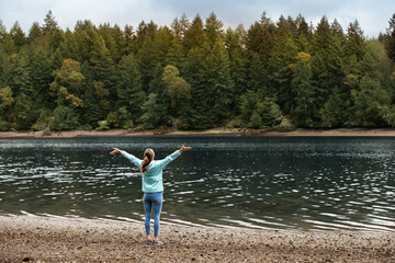 Fototapeta na wymiar Young relaxed woman in sweater enjoying nature breathing fresh air meditating feeling joyful on the river 