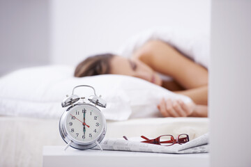 Sleeping, morning and woman in bed with alarm for snooze, wake up and start day in home. Lazy, tired and person resting, dreaming and relaxing in bedroom with time, clock and glasses in house - obrazy, fototapety, plakaty