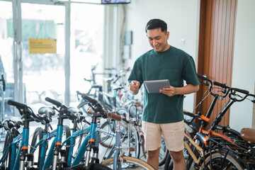 young man checks out a new bike while using a tablet at a bike shop