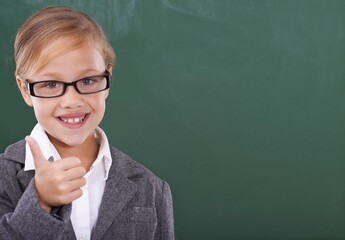 Child by chalkboard, thumbs up and education, learning or school success, like and support with mockup space. Portrait of of happy kid, girl or student in glasses with yes and ok hands in classroom