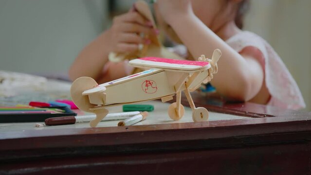 Asian girl is coloring on assembly wooden toy with magic color