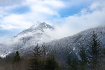 snow covered mountains during a foggy day with clouds rolling over