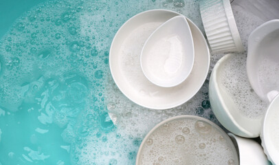 Plates and bowl soaking in foam of dishwashing liquid