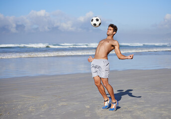 Man, beach and playing with soccer ball for game, sports or exercise in outdoor hobby, training or practice. Young muscular male person or football player in match or cardio workout by ocean coast