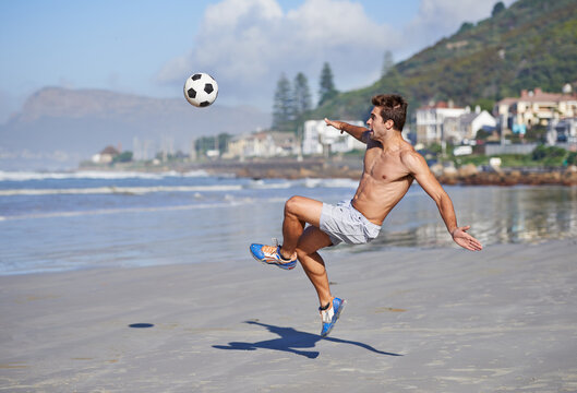 Man, beach and volley with soccer ball for game, sports or exercise in outdoor hobby, training or practice. Young male person or football player kicking in match or cardio workout by ocean coast - Powered by Adobe