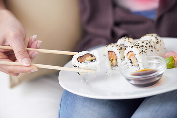 Hands, sushi plate and chopsticks in closeup, home or eating for wellness, diet or meal with soy...