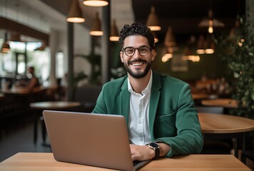 Portrait of a smiling businessman using laptop while sitting in a cafe