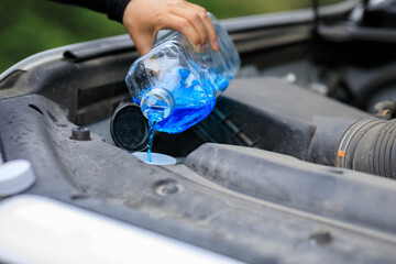 pouring blue non reezing windshield glass washer fluid into the tank
