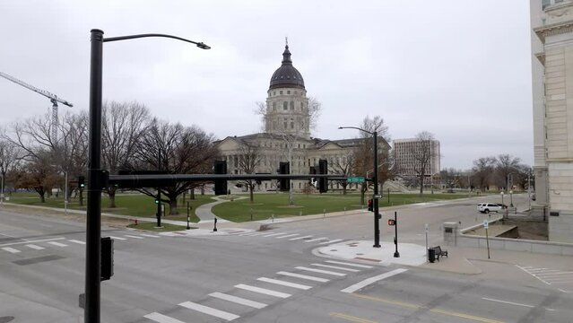 Kansas state capitol building with flags waving in wind in Topeka, Kansas with drone video pulling back.