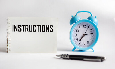 INSTRUCTIONS The word is written in a notepad with a pen and a clock on a white background....