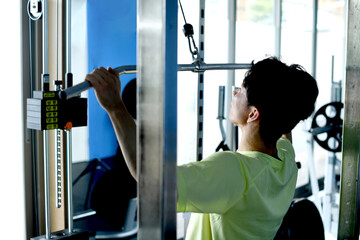 ジムでマシントレーニングをする若いアジア人男性の後ろ姿