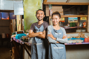 smiling Asian man and woman wearing apron standing at a traditional stall