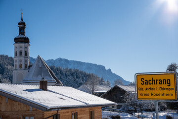 Church tower and town sign of the mountaineering village of Sachrang in Chiemgau, Bavaria, Germany...