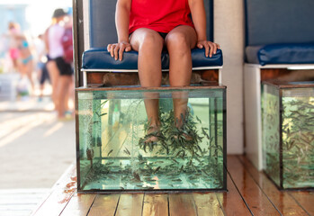 A girl on her feet is peeling fish in an aquarium