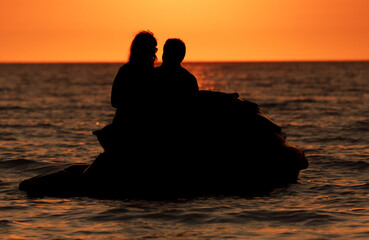 Man woman on a jet scooter on the sea at sunset