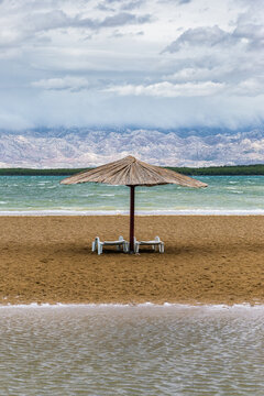 Nin, Croatia - Reed sunshade at the empty Queen's Beach by the mediterranean town of Nin at the end of summer with Velebit Mountains at background and turquoise Adriatic sea water at autumn time