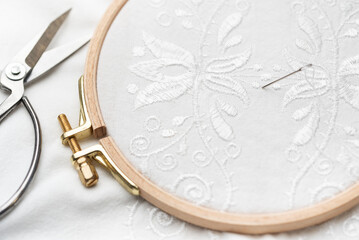 The process of embroidering a shirt with white threads on white fabric.