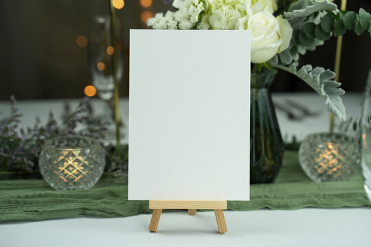 Mockup white blank space card, for greeting, table number, wedding invitation template on wedding table setting background. with clipping path