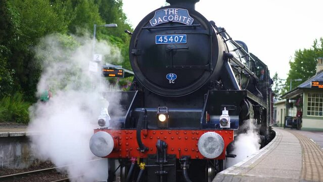 Jacobite train, steam locomotive for tourist, coming from Glenfinnan viaduct bridge in Scotland. Jacobite Railway scenic tourism attraction in Britain. 