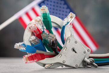 Closed handcuffs on network wires and the USA flag on an abstract background, concept on the theme...