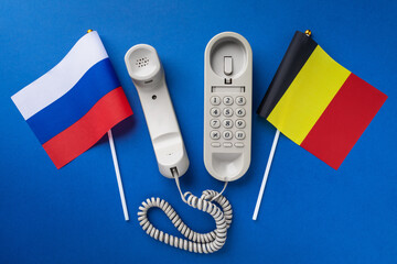 Old telephone and two flags on a blue background, concept on the theme of telephone conversations...