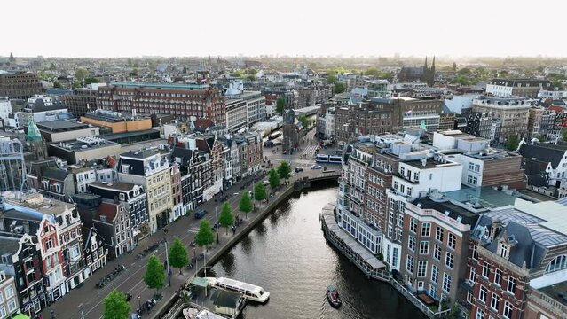 The drone is flying above the city centre going sideways looking at Muntplein with the sun shining in Amsterdam The Netherlands Aerial Footage 4K