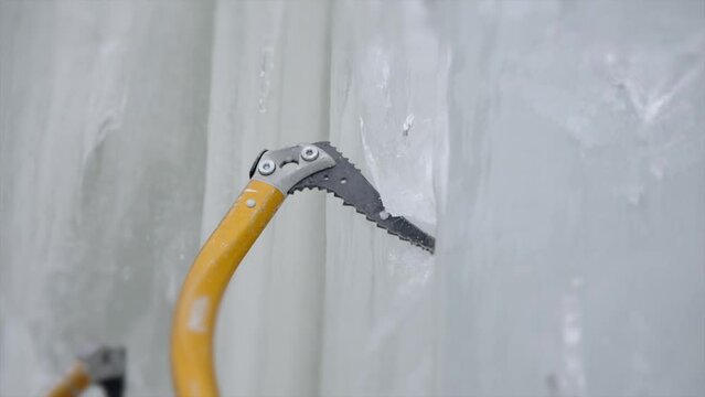 Winter mountaineer uses ice axe climbing technique in frozen rock SLO MO
