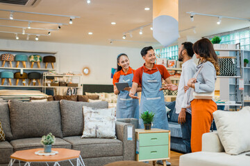 two shop assistants chat as they let customers view new furniture products at a furniture store