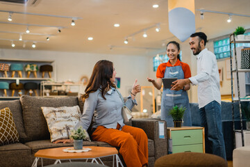 female customer enjoys trying to sit on the sofa while the waitress serves the customer looking at...