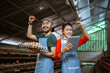 entrepreneur couple carrying cardboard tray for chicken eggs and tablet with gesture celebrate...