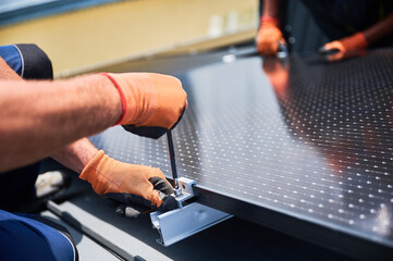 Worker building photovoltaic solar panel system on rooftop of house. Close up of man engineer in...